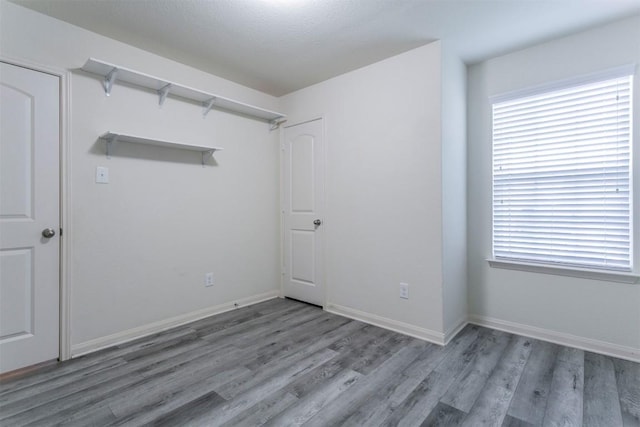 spare room featuring wood finished floors, plenty of natural light, and baseboards
