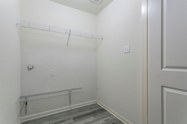 clothes washing area with wood finished floors and baseboards