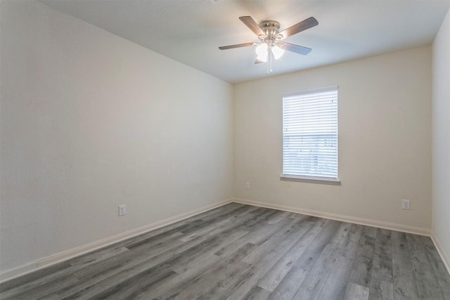 empty room featuring wood finished floors, baseboards, and ceiling fan