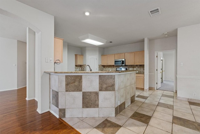 4329 Rock Hill Rd, Round Rock, TX 78681 - kitchen with stainless steel microwave, light brown cabinetry, tasteful backsplash, a peninsula, and a sink