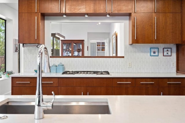 kitchen featuring light countertops, tasteful backsplash, white gas stovetop, and a sink
