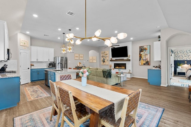 115 Oleander Loop, Buda, TX 78610 - dining area with wood finished floors, a warm lit fireplace, recessed lighting, and arched walkways