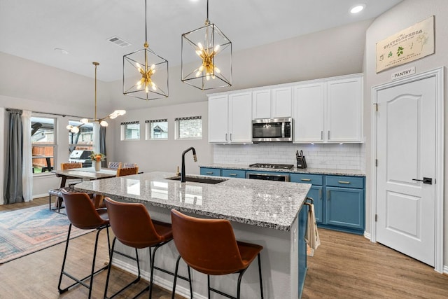 115 Oleander Loop, Buda, TX 78610 - kitchen featuring blue cabinets, stainless steel microwave, high vaulted ceiling, a chandelier, and white cabinets