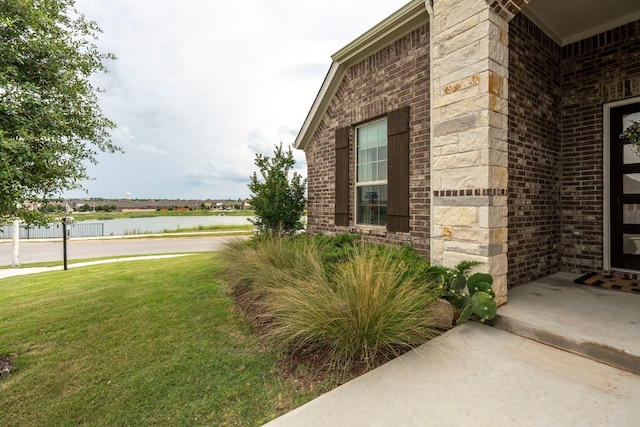 115 Oleander Loop, Buda, TX 78610 - property entrance with brick siding, a water view, a yard, and stone siding