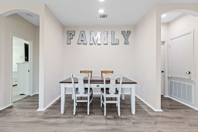 dining room with wood finished floors, baseboards, and arched walkways