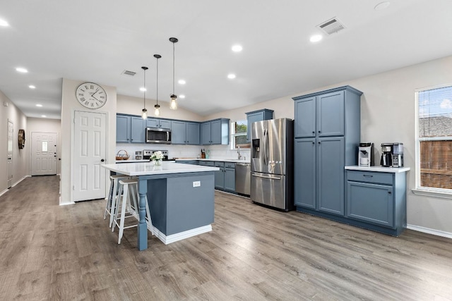 kitchen featuring appliances with stainless steel finishes, blue cabinetry, light wood-type flooring, light countertops, and a sink