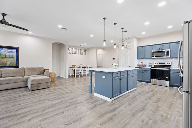 kitchen featuring stainless steel appliances, arched walkways, open floor plan, light wood finished floors, and recessed lighting