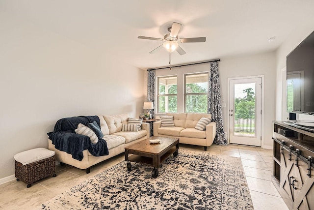 living area featuring light tile patterned floors, a ceiling fan, and baseboards