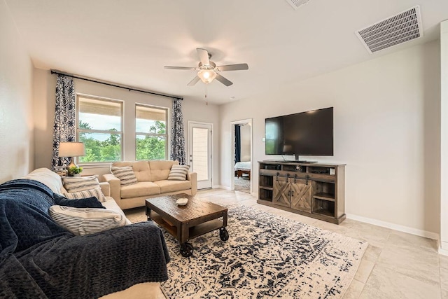 tiled living room with a ceiling fan and baseboards