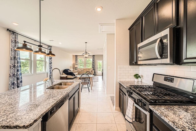 kitchen featuring stainless steel appliances, a sink, tasteful backsplash, light stone countertops, and recessed lighting