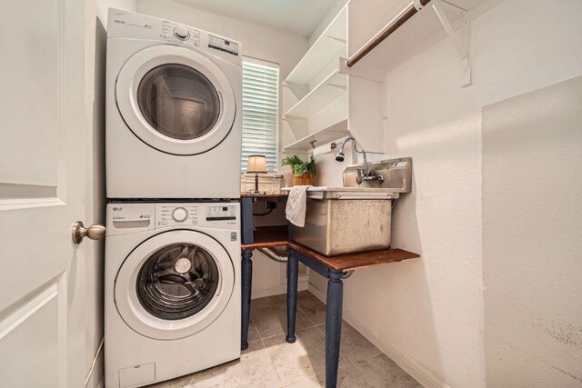 clothes washing area with stacked washer and clothes dryer, tile patterned floors, and baseboards