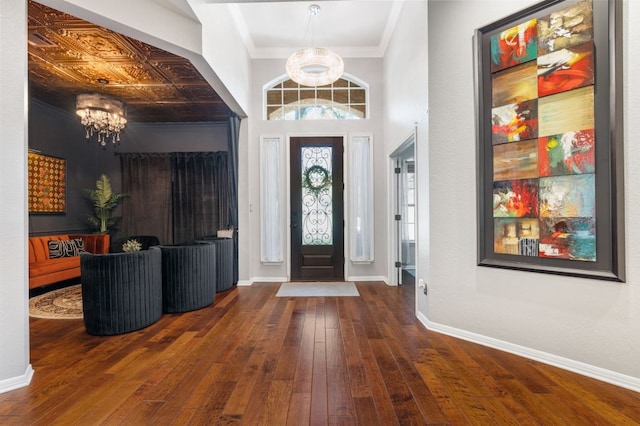 entrance foyer featuring a chandelier, hardwood / wood-style flooring, baseboards, and crown molding