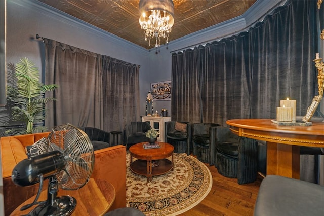 living area featuring wood finished floors, a chandelier, an ornate ceiling, and ornamental molding