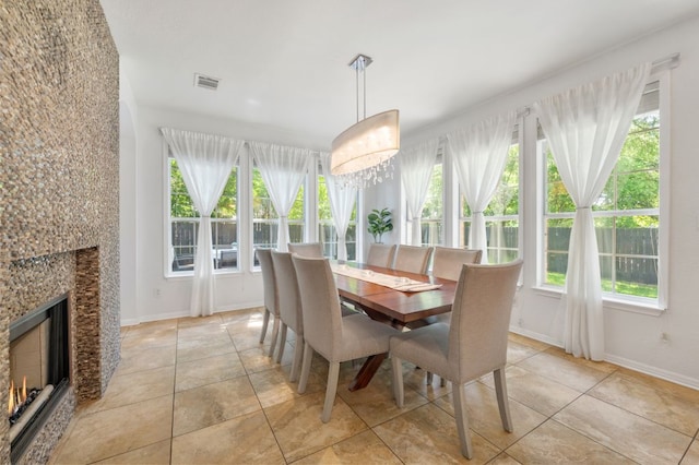 dining area with healthy amount of natural light, light tile patterned flooring, and a lit fireplace
