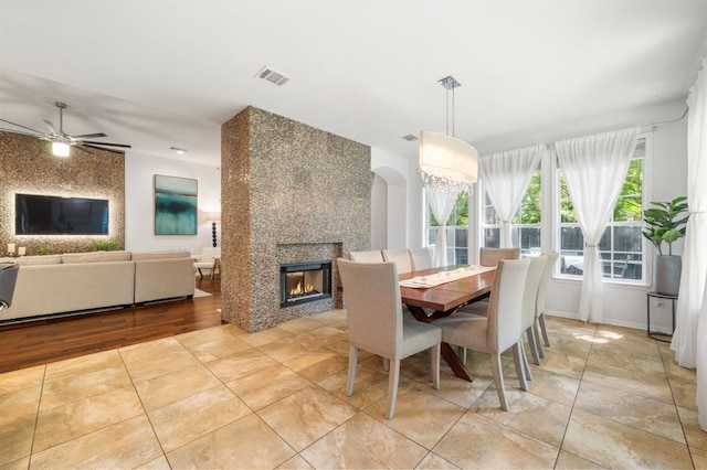 3016 Sunland Dr, Austin, TX 78748 - dining area featuring a fireplace, ceiling fan, light tile patterned floors, and arched walkways