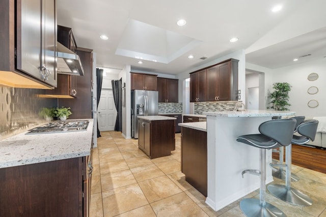 3016 Sunland Dr, Austin, TX 78748 - kitchen with appliances with stainless steel finishes, a peninsula, exhaust hood, tasteful backsplash, and dark brown cabinets
