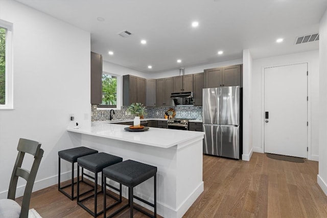 1208 W Oltorf St Unit B, Austin, TX 78704 - kitchen with stainless steel appliances, a breakfast bar, light countertops, tasteful backsplash, and a peninsula