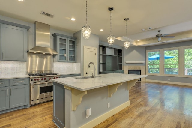 2112 W 11th St, Austin, TX 78703 - kitchen with wall chimney exhaust hood, a sink, premium range, gray cabinetry, and light stone countertops