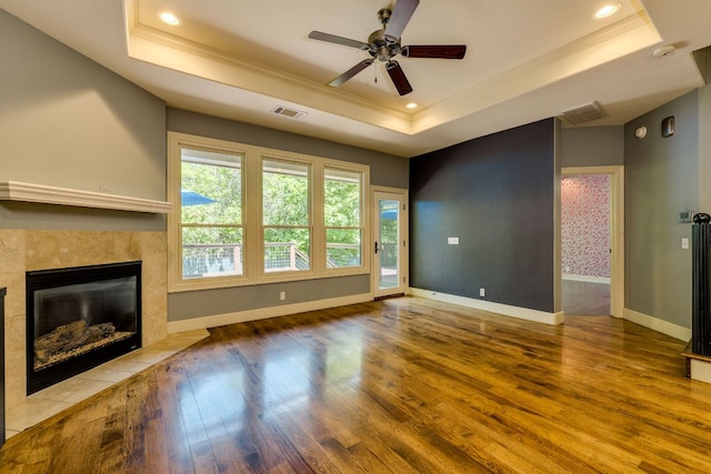 2112 W 11th St, Austin, TX 78703 - unfurnished living room with a raised ceiling, crown molding, wood finished floors, a tile fireplace, and a ceiling fan