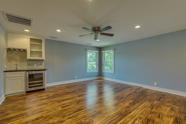 2112 W 11th St, Austin, TX 78703 - empty room with beverage cooler, a bar, dark wood-style flooring, ceiling fan, and baseboards