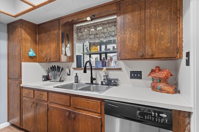 kitchen with dishwasher, a sink, light countertops, and brown cabinetry