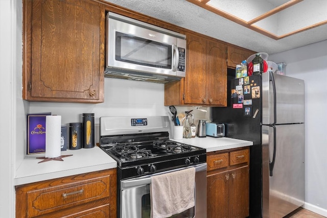kitchen featuring appliances with stainless steel finishes, brown cabinets, and light countertops