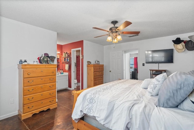 bedroom featuring concrete flooring, baseboards, a textured ceiling, a ceiling fan, and ensuite bathroom