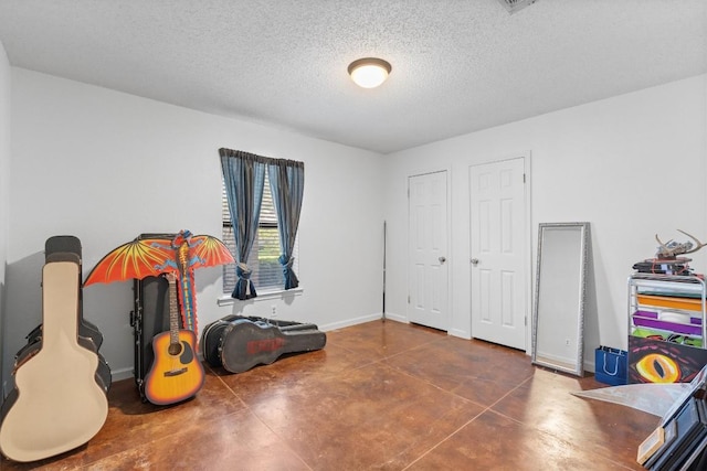 rec room with concrete floors, a textured ceiling, and baseboards