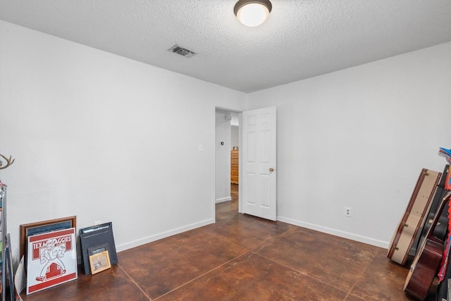unfurnished bedroom with a textured ceiling, baseboards, and concrete flooring
