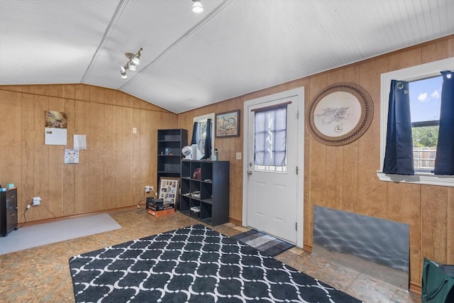 foyer with vaulted ceiling and wood walls