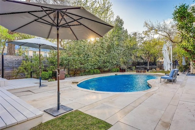 swimming pool with a fenced backyard, a wooden deck, and a patio