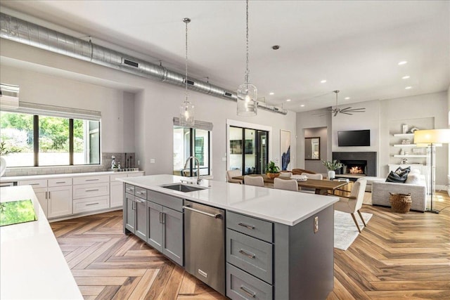 27 Wingreen Loop, The Hills, TX 78738 - kitchen with stainless steel dishwasher, gray cabinets, a ceiling fan, a warm lit fireplace, and light countertops