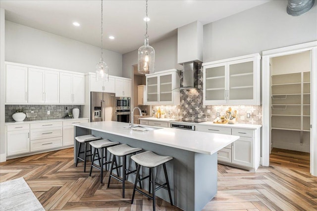 27 Wingreen Loop, The Hills, TX 78738 - kitchen with appliances with stainless steel finishes, wall chimney exhaust hood, a breakfast bar, a kitchen island with sink, and decorative backsplash