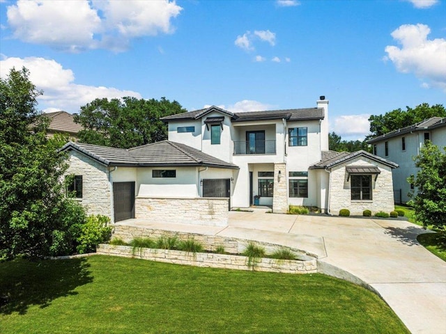 27 Wingreen Loop, The Hills, TX 78738 - contemporary house featuring stone siding, stucco siding, a balcony, a chimney, and a front lawn