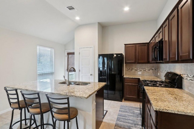 6032 Urbano Bnd, Round Rock, TX 78665 - kitchen with black appliances, a kitchen island with sink, dark brown cabinets, light tile patterned floors, and backsplash