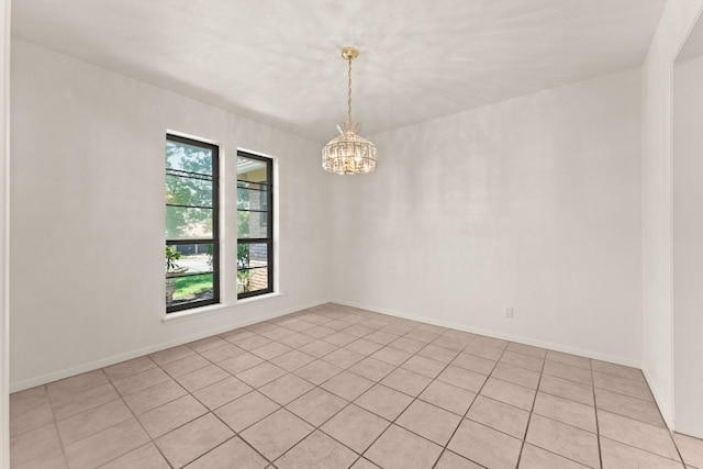 empty room with a chandelier, light tile patterned flooring, and baseboards