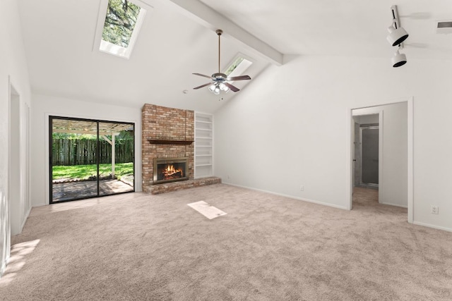 unfurnished living room featuring a skylight, carpet floors, a brick fireplace, ceiling fan, and beam ceiling