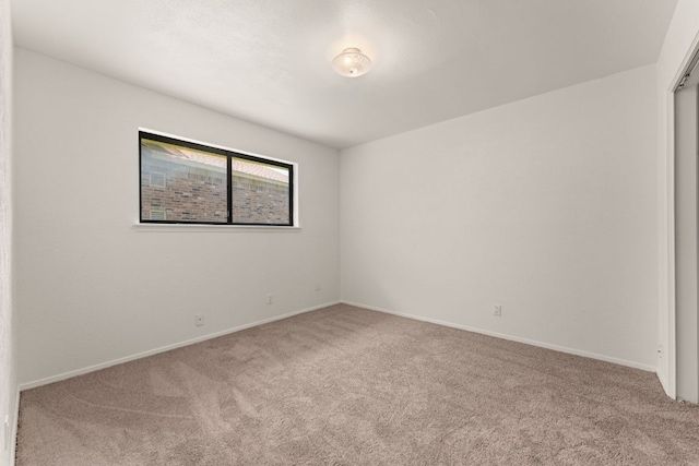 carpeted empty room featuring baseboards