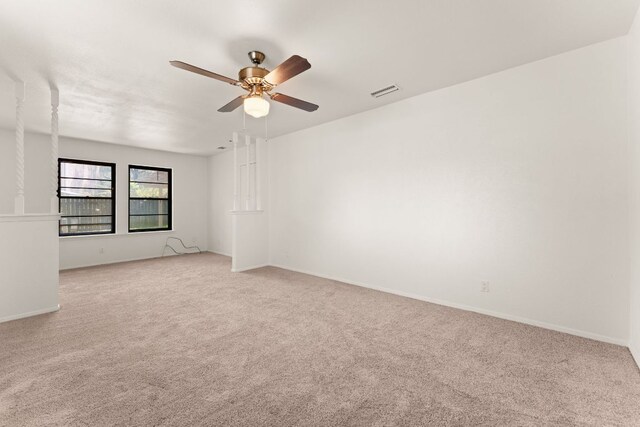 spare room featuring a ceiling fan, light colored carpet, and baseboards