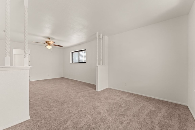 spare room with light carpet, a ceiling fan, and baseboards