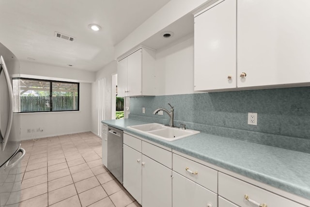 kitchen with a sink, stainless steel appliances, white cabinetry, decorative backsplash, and light countertops