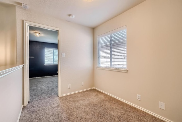 carpeted spare room featuring baseboards