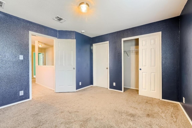 unfurnished bedroom featuring carpet floors, a textured wall, baseboards, and a closet