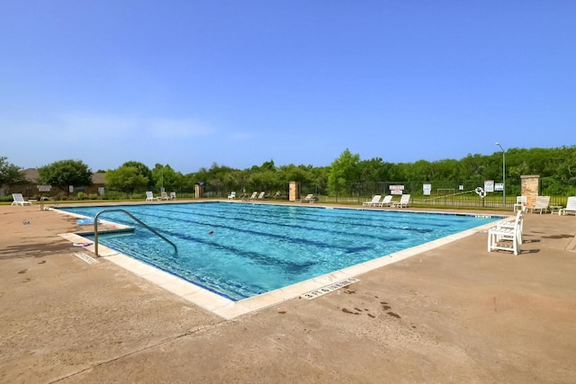 community pool with a patio area and fence