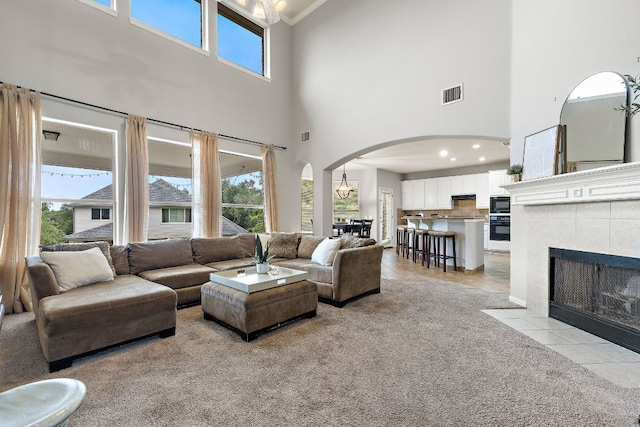 3805 Durnberry Ln, Round Rock, TX 78664 - living area featuring a towering ceiling, arched walkways, light carpet, ornamental molding, and a tiled fireplace