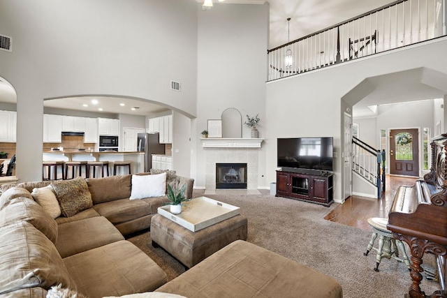 3805 Durnberry Ln, Round Rock, TX 78664 - living room with a towering ceiling, a tile fireplace, carpet floors, stairway, and arched walkways