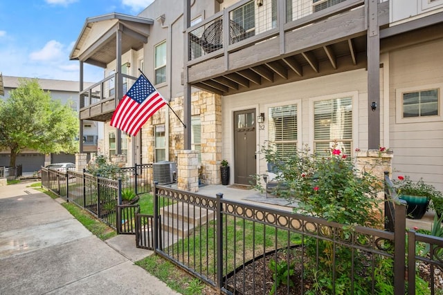 2520 Bluebonnet Ln Unit 32, Austin, TX 78704 - entrance to property featuring stone siding, a balcony, fence, and central AC
