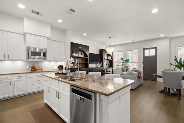2520 Bluebonnet Ln Unit 32, Austin, TX 78704 - kitchen with stainless steel appliances, a sink, an island with sink, wood finished floors, and decorative backsplash