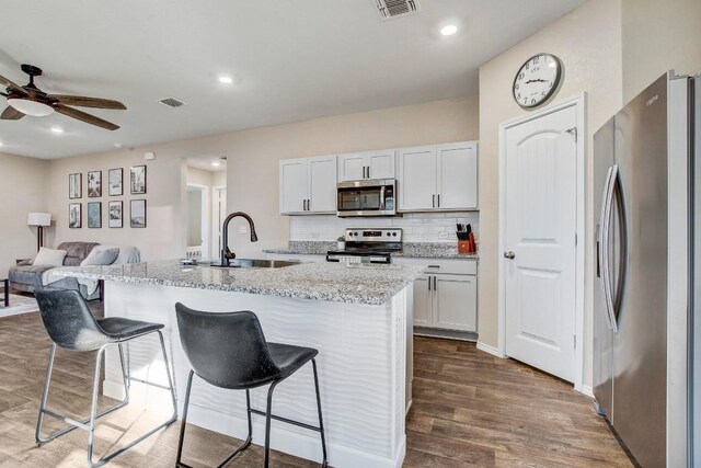 12224 Token Trl, Elgin, TX 78621 - kitchen featuring appliances with stainless steel finishes, a sink, a breakfast bar area, dark wood finished floors, and ceiling fan