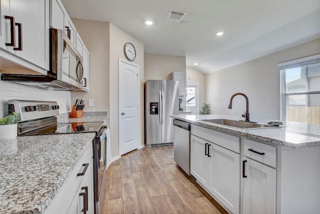 12224 Token Trl, Elgin, TX 78621 - kitchen featuring stainless steel appliances, a sink, light wood-type flooring, a center island with sink, and light stone counters